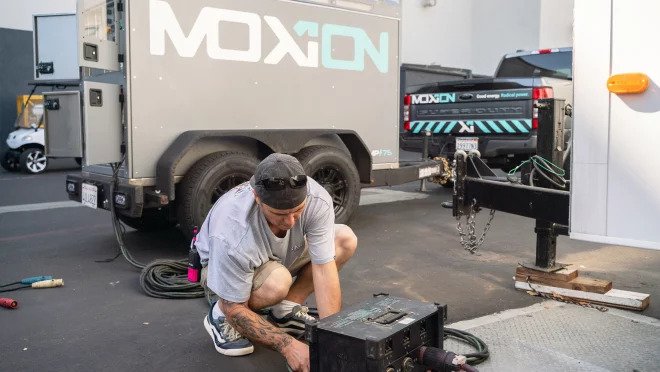 Crouched man working on a machine on the street