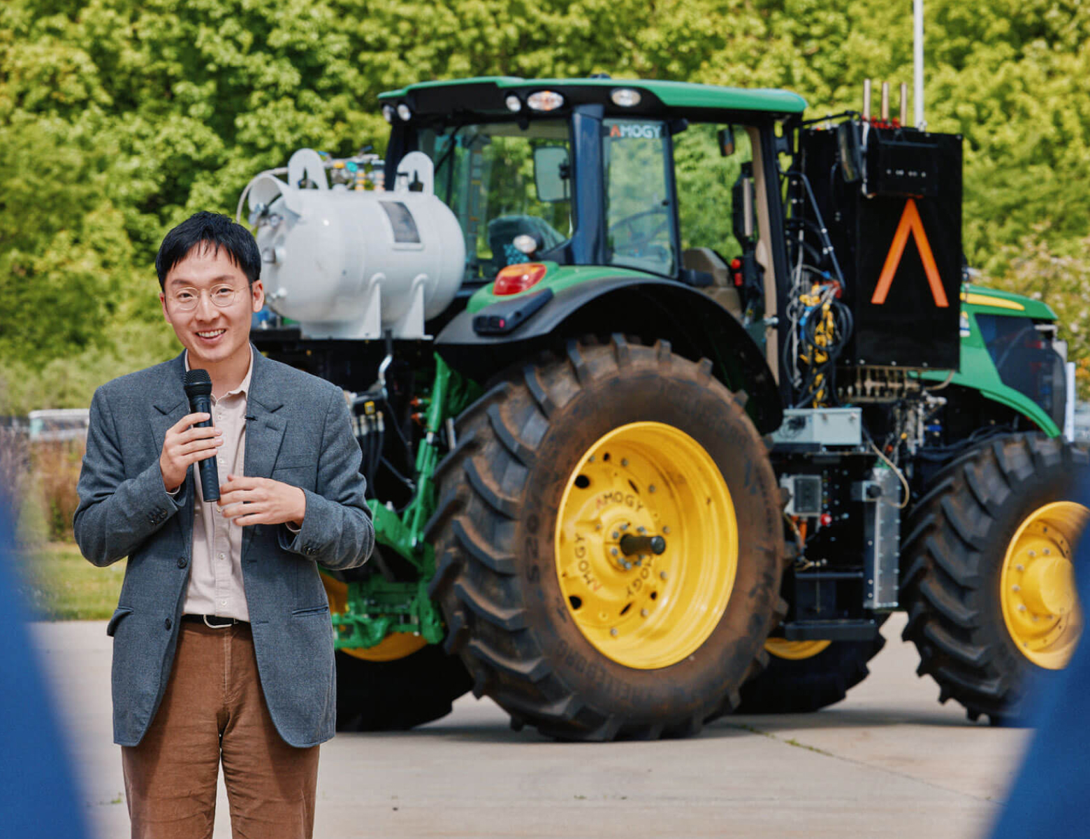 Man holding microphone and standing in front of ammonia-powered tractor